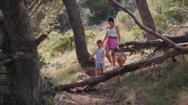 Annem, çocuklar el ele tutuşurken parkta yürüyor. Mutlu ve gülümseyen bir aile ormanda birlikte yürüyüp birlikte zaman geçiriyorlar..