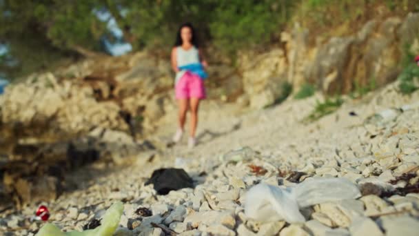 ゴミから自然をきれいにする 少女は海のそばの袋にゴミやプラスチックを集めます 世界の海の汚染ときれいな環境のための人間のひげ — ストック動画