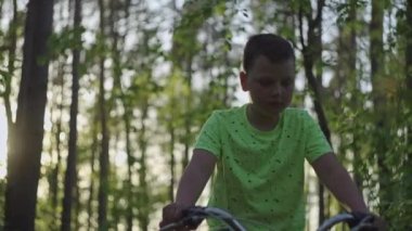 Ormanda bisiklet süren genç bir çocuğun yakın çekimi. Doğada bir çocuğun aktif olarak yeniden yaratılması, off-road bisiklet.