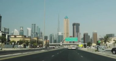 Hareket halindeki video Dubai. Camdan gökdelenleri olan büyük bir şehrin şehir merkezine giden yolun çerçevesi. Evlerin örümceklerinin caddelerini görebileceğiniz güzel bir manzara..