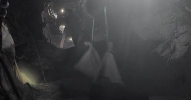 Madenin tepesine kadar taşlı çantaların ve arka planda kafasında lambalar olan insanların gittiği tüneli. Afrika 'daki maden endüstrisinin güzel bir videosu..