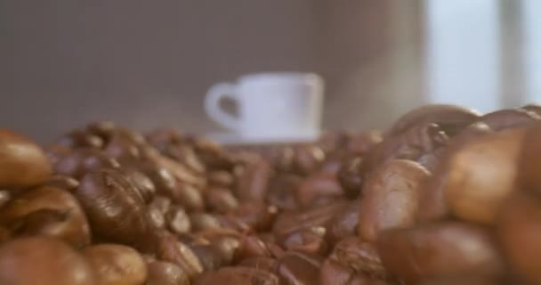 朝のコーヒーを飲みながらマグカップ フレッシュなエスプレッソの香りが漂うカプチーノは コーヒー豆がのったテーブルの上に立っています ロゴのためのパックショット — ストック動画