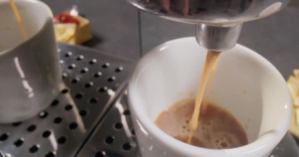 キッチンで自宅でコーヒーを作る エスプレッソやアメリカーノは コーヒーメーカーのカップに注ぎ プレートの上に置かれ 朝食のための朝の飲み物です 4Kスローモーションビデオ — ストック動画