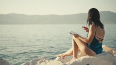 Albümde mayo giymiş güzel bir Avrupalı kız denizi çiziyor. Okyanus kıyısındaki bir kadın hobileri ve yaratıcılığıyla meşgul olur. Yüksek kalite 4k görüntü