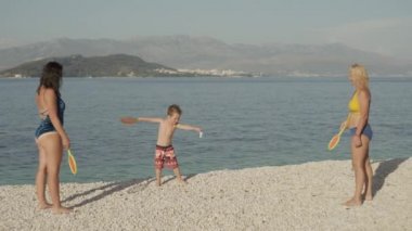 Okyanus kıyısında tenis oynayan bir ailenin yavaş çekim videosu. Çocuklarla boş zamanlarında aktif sporlar..