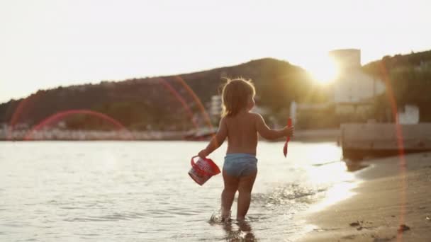 해변에서 소녀의 아름다운 아기가 휴가를 즐기며 바다를 고품질 — 비디오
