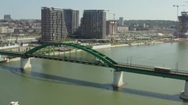 Kırmızı tramvayın Sava nehrinden geçtiği demir köprünün üzerinden insansız hava aracı uçuşu. Şehir arkaplanı ve güzel şehir manzarası.