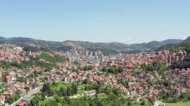Uzice Serbia 'yı havadan çektiler. İnsansız hava aracı, evleri, sokakları, manzaraları, şehir merkezini ve birçok kırmızı çatıyı gördüğümüz dağlarla çevrili bir şehrin videosudur..