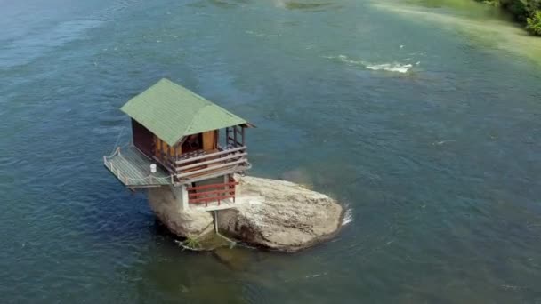 空射向塞尔维亚 无人机视频中 一座小房子矗立在河中央的岩石上 你可以看到岩石 森林和树木 还有美丽的山水 — 图库视频影像