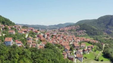 Uzice Serbia 'yı havadan çektiler. İnsansız hava aracı, evleri, sokakları, manzaraları, şehir merkezini ve birçok kırmızı çatıyı gördüğümüz dağlarla çevrili bir şehrin videosudur..