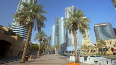 Dubai 'de palmiye ağaçları ve gökdelenleri olan bir cadde. Arabaların sürdüğü caddelerde cam gökdelenleri olan şehir manzarası. Orta Doğu 'nun modern mimarisi
