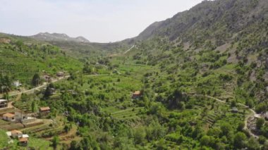Lübnan dağlarında çiftlikleri olan bir köyün havadan görünüşü. Kırsal evler üzüm bağlarının ve meyve bahçelerinin yetiştiği bir yamaçta duruyor. Rocky dağları güzel bir manzarada.