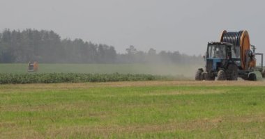 Traktör vuruşu. Tekerleklerinin altından mısır ve toz dolu bir alanda yelken açmak için hortumları olan büyük bir traktör çıkacak..