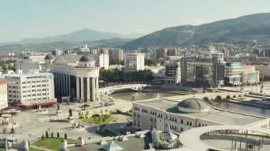 Üsküp Makedonya 'nın havadan görünüşü. İnsansız hava aracı şehir merkezindeki evlerin üzerinde caddeler, parlamento ve Vardar nehri boyunca köprüler ve gemilerle anıtlar uçurdu. Yüksek kalite 4k görüntü