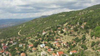 Orman ve tepeleri olan dağlarda evleri ve kırmızı çatıları olan bir köyün insansız hava aracı videosu. Makedonya 'yı hava saldırısı vurdu. Yüksek kalite 4k görüntü
