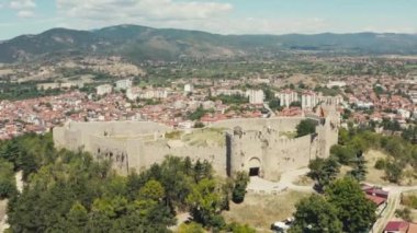 Hava saldırısı Ohri Makedonya 'yı vurdu. Kırmızı çatıları ve güzel manzarası olan evleri olan bir şehirle çevrili bir dağın tepesinde duran kuleleri olan bir kalenin insansız hava aracı videosu. Yüksek kalite 4k görüntü