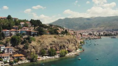 Dağın tepesinde kırmızı çatıları olan güzel manzaralı bir gölün kıyısında duran bir şehrin insansız hava aracı videosu. Hava manzaralı Ohri Makedonya. Yüksek kalite 4k görüntü