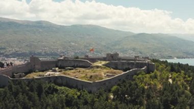 Hava saldırısı Ohri Makedonya 'yı vurdu. Kırmızı çatıları ve güzel manzarası olan evleri olan bir şehirle çevrili bir dağın tepesinde duran kuleleri olan bir kalenin insansız hava aracı videosu. Yüksek kalite 4k görüntü