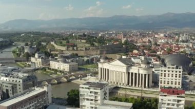 Şehir merkezinde eski evlerle çevrili köprülerle nehir kıyısında duran parlamento binasının insansız hava aracı videosu. Üsküp Makedonya 'yı Arial vurdu. Yüksek kalite 4k görüntü