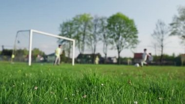 Çocuklar çimlerin üzerinde futbol oynuyor. Topla oynayan iki çocuk aktif olarak doğada vakit geçiriyorlar, bir takım oyunu oynuyorlar..