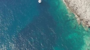 Deniz ya da okyanus manzarası, kayalık bir dağın yüksek uçurumunda dalgalar kopuyor ve yakınlarda bir yat yüzüyor. Adriyatik Denizi 'nin kayalık kıyıları, Karadağ. Yüksek kalite 4k görüntü