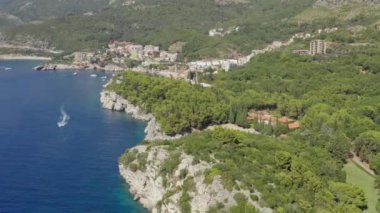 Okyanus ya da denizin kayalık bir dağı ve yakınlarda giden bir teknesi olan insansız hava aracı videosu. Adriyatik Denizi 'nin kayalık kıyıları, Karadağ. Yüksek kalite 4k görüntü