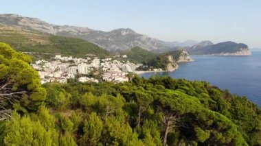 Karadağ 'daki Adriyatik Denizi kıyısındaki Petrovac kasabası. Arka planda dağ manzarası ve marinası olan koyu kırmızı fayanslı evler olan bir kasaba. Yüksek kalite 4k görüntü