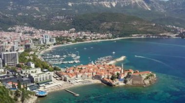 Budva Karadağ havadan vuruldu. Adriyatik kıyısındaki bir şehrin insansız hava aracı videosu dağlarla çevrili güzel bir manzarayla, eski ve yeni bir şehirle. Yüksek kalite 4k görüntü