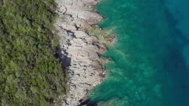 Deniz ya da okyanus manzarası, kayalık bir dağın yüksek uçurumunda dalgalar kopuyor ve yakınlarda bir yat yüzüyor. Adriyatik Denizi 'nin kayalık kıyıları, Karadağ. Yüksek kalite 4k görüntü