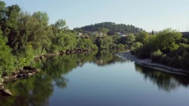 Karadağ Podgorica 'yı hava saldırısı vurdu. Nehir üzerinde güzel bir insansız hava aracı uçuşu ve şehirde ağaçlar, evler ve güzel manzaralı bir köprü. Yüksek kalite 4k görüntü