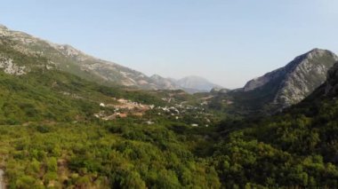 Karadağ 'daki Adriyatik Denizi kıyısındaki hava manzaralı kasaba. Arka planda dağ manzarası ve marinası olan koyu kırmızı fayanslı evler olan bir kasaba. Yüksek kalite 4k görüntü