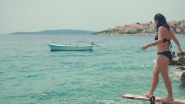女孩从海边的码头跳进了水里 美丽快乐的女人在海边度假 慢动作视频的顶部视图 — 图库视频影像