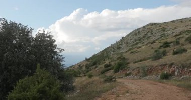 Makedonya dağlarında güzel bir yol. Dağların arasında kayalar, ağaçlar, taşlar ve arka planda dağ tepeleri ve tepeler var. Yüksek kalite 4k görüntü