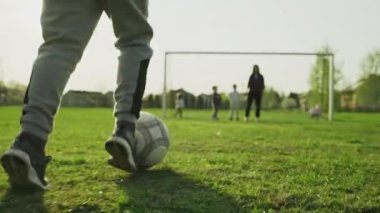 Anne ve çocuklar stadyumda futbol oynuyorlar. Yavaş çekim video ailesi futbol, açık hava aktiviteleri ve takım çalışmasıyla zaman geçiriyor. Çocuk topu kaleye doğru götürüyor..