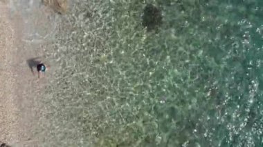 Manzaralı kız kıyıdan geliyor ve berrak deniz suyuna dalıyor. Yaz tatilinde güzel bir kadın okyanusta yüzüyor..