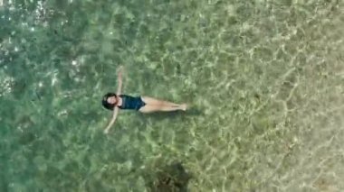 Hava manzaralı kız mavi denizde yüzüyor. Kadın yaz tatilinde okyanusta uzanır ve dinlenir..
