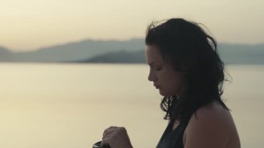 Deniz kenarında sabah kahvesi içen bir kız. - Evet. Yüksek kalite 4K görüntü. Okyanus kenarında güzel bir şafak ve bir fincan çayla tek başına dinlenen bir kız..