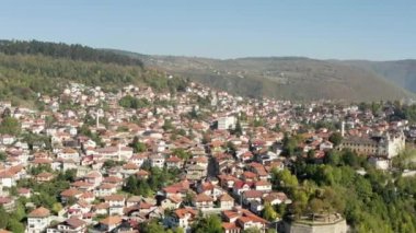 Şehrin eski mahallesinde kırmızı çatılı evler, kiliseler, camiler ve güzel bir dağ manzarası olan insansız hava aracı uçuyor. Saraybosna Bosna-Hersek 'in hava manzarası.