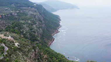 Kayalık kıyı şeridinin havadan görüntüsü. Bir dronun, kayanın sıradağları ve tepeleri kozalaklı ağaçlarla kaplanmış ve Akdeniz 'in dalgalarıyla yıkanmış bir şekilde uçuşu..
