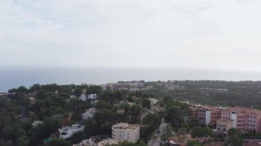 Şehir sokaklarının kentsel manzarası dron 4K video. Dağların ve denizin arka planına sahip çam ağaçları olan ormanlarla çevrili bir tepenin üzerindeki evlerin üzerindeki hava manzarası. Yüksek kalite 4k görüntü