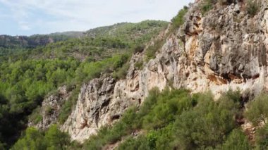 Dağ tepesi dron 4K video ile manzara kayaları. Uçurumların havadan görünüşü, arka planda ormanları olan dağ sıraları. Yüksek kalite 4k görüntü