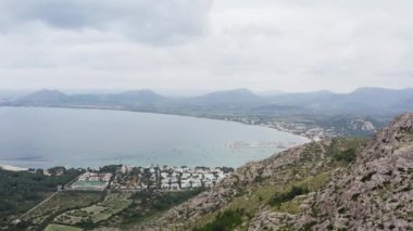 Akdeniz dron 4K videosundaki dağlardaki şehir. Gökyüzü manzaralı evler ve sokaklar, deniz dalgalarının çarptığı çam ağaçları ile dağların zirvelerinde duruyor. Yüksek kalite 4k görüntü