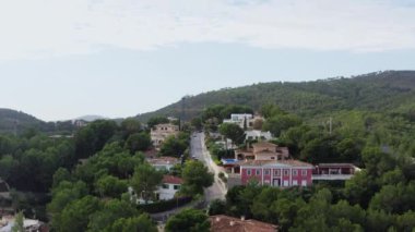 Urban landscape of city streets dron 4K video. Aerial view over houses standing on a hill surrounded by forests with pine trees with a background of the sea and mountains. High quality 4k footage