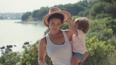 Anne deniz kenarında kızıyla güzel bir şekilde oynuyor. Mutlu çocukluk ve ebeveyn aşkı, mutlu bir takım gibi, kız kafasından kadın şapkası çıkarıyor..