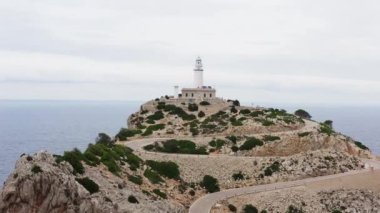 Kaya dron 4K videosundaki deniz feneri. Akdeniz 'in dalgalarının çarptığı kayanın havadan görünüşü ve tepesinde bir deniz feneri binası var. Yüksek kalite 4k görüntü