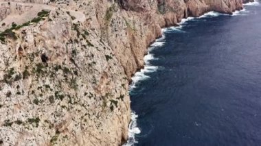 Rocky ocean shoreline dron 4K video. Aerial view of the sea waves crashing against a high mountain in a beautiful landscape. High quality 4k footage