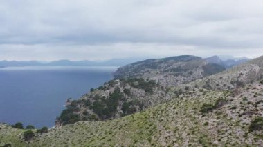 Rocky mountain ranges dron 4K video. Aerial view Beautiful landscape of mountains with peaks, cliffs on which grow bushes with a background on the sea waves. High quality 4k footage