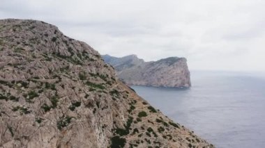 Akdeniz dron 4K videosunun yakınlarındaki sıradağlar. Üzerinde ağaçlar ve ormanlar yetişen kayalar ve uçurumlarla dolu dağların tepeleri denizin dalgalarıyla yıkanır.. 