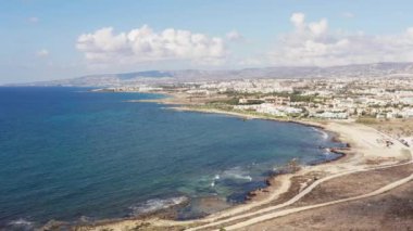 Kıbrıs Rum Kesimi 'nin deniz manzarası. Akdeniz 'in dalgaları tarafından yıkanan sarı kumsallı bir lagünü olan kayaların ve dağların üzerinden uçan dron. Yüksek kalite 4k 