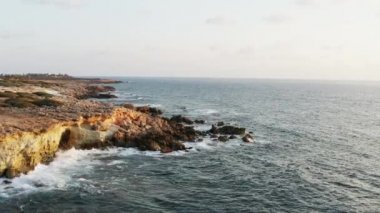 İnsansız hava aracı, dalgaların kayalara ve kayalıklara çarptığı Akdeniz 'deki adanın kayalık kıyılarında uçuyor. Kıbrıs 'ın kıyı şeridi havadan izleniyor. Yüksek kalite 4k görüntü